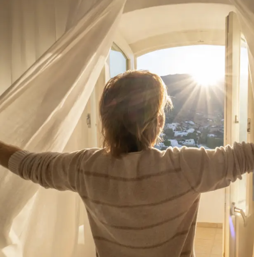 man standing at a sunlit window with arms open, finding relief from high-functioning anxiety in Beverly Hills