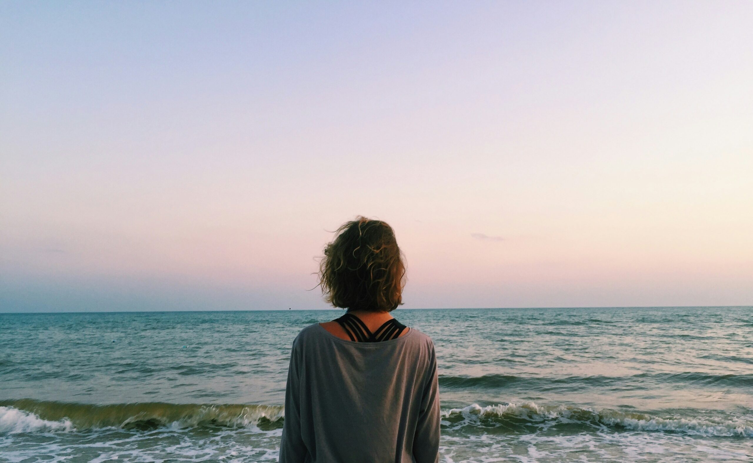 Woman by the water in soft light, reflecting on healing from a trauma bond