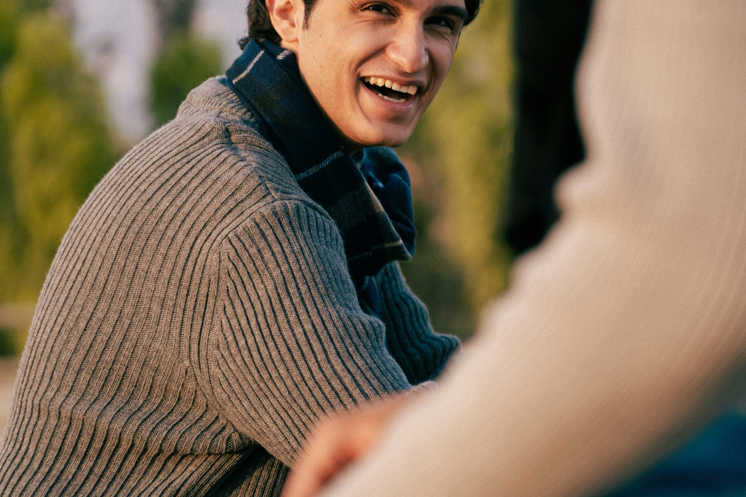 A people pleaser laughing warmly with a friend, at ease after letting go of the pattern